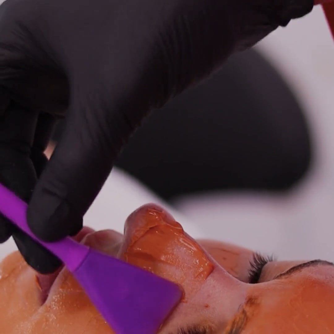 Profissional aplicando máscara de tratamento no rosto com espátula
