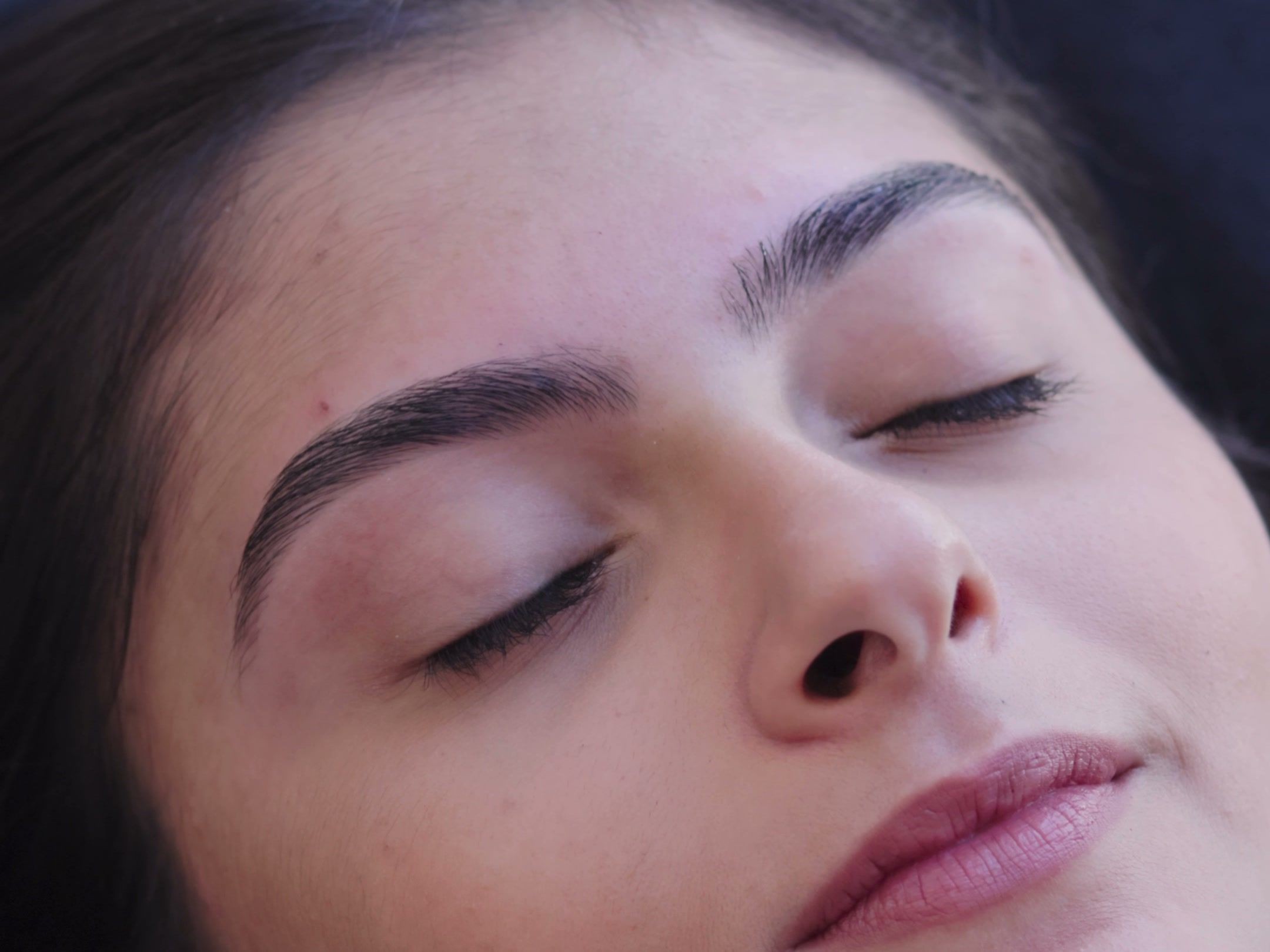 Cliente de olhos fechados com sobrancelhas bem desenhadas depois do design na Clínica da Barbe